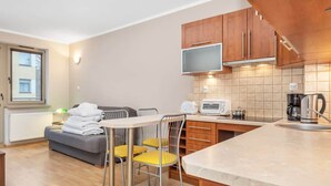 Un espace de vie compact comprenant un coin cuisine, un espace repas avec une table et des chaises, un canapé et une fenêtre.
