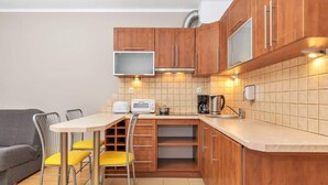 Une cuisine compacte avec des meubles en bois, un four à micro-ondes encastré, un grille-pain et une machine à café.