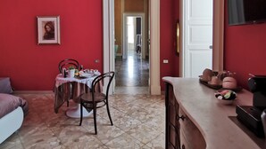 A room with red walls, a dining area with a table and chairs, a TV mounted on the wall, and a kitchen counter with various items. - Chez Moi Lecce Charme B&B (Lecce)