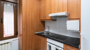 Une cuisine avec des meubles de rangement en bois, une cuisinière, un évier et un réfrigérateur.