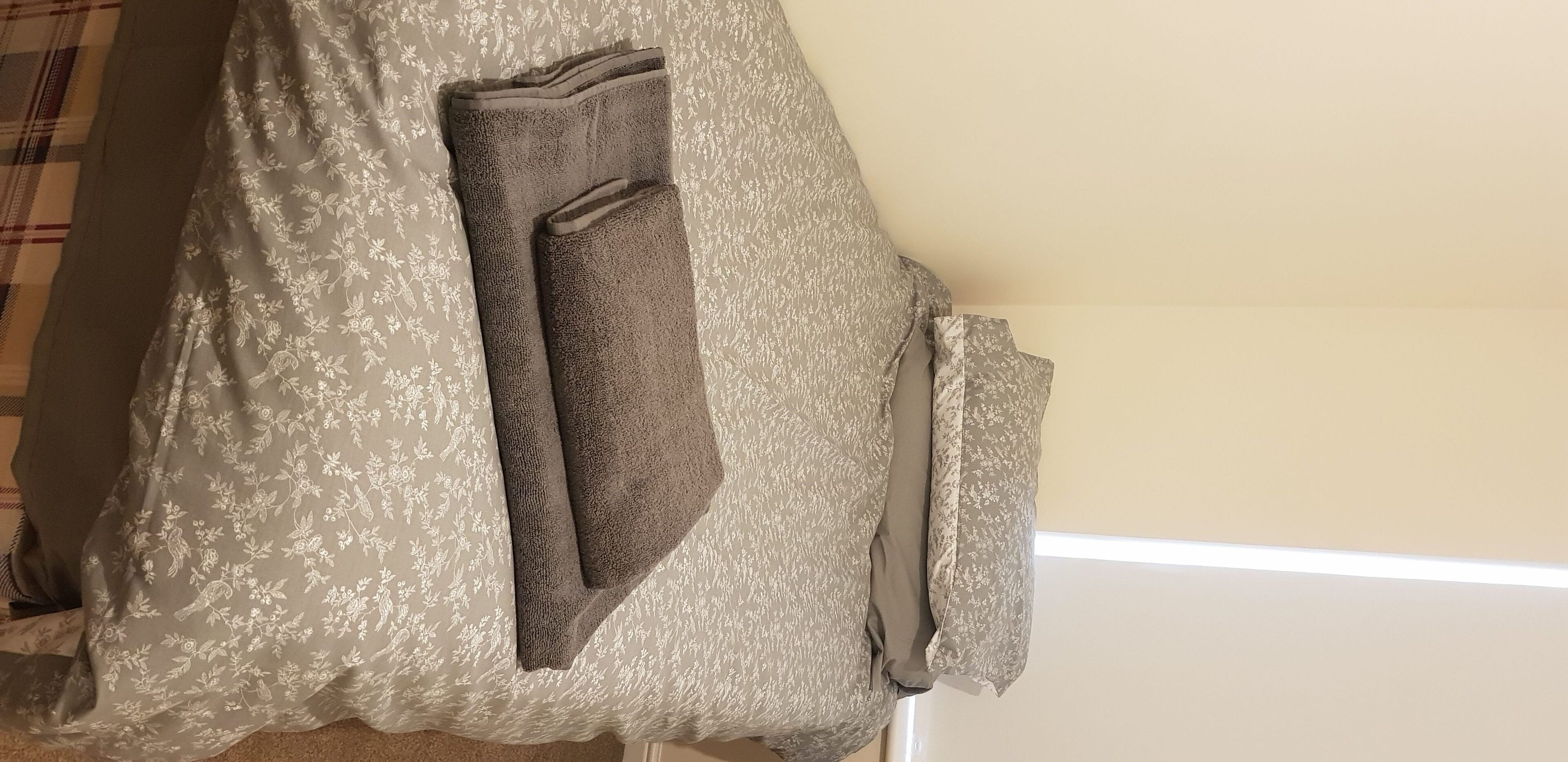 A bed with a floral-patterned bedspread and a folded blanket.