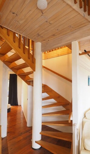 A wooden staircase with white columns, leading to an upper floor. - Ocean Views Sleeps 20 (Fraser Island)