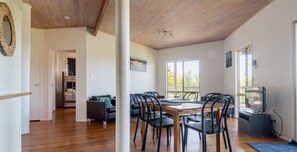 A dining area with a wooden table and chairs, a television, and a view of the outdoors. - Ocean Views Sleeps 20 (Fraser Island)