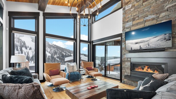 A spacious living room with large windows, a fireplace, and comfortable seating. - Ski-in/Ski-Out Luxury Schweitzer•Hot Tub•4 King Suites•Walk to Village•Ski Room (Sandpoint)