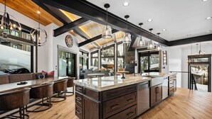 A spacious kitchen with a large island, wooden flooring, and modern pendant lighting. - Ski-in/Ski-Out Luxury Schweitzer•Hot Tub•4 King Suites•Walk to Village•Ski Room (Sandpoint)