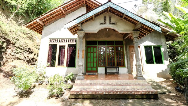 A traditional house with a tiled roof, a green door, and a small porch. - JIO Homestay (Yogyakarta)