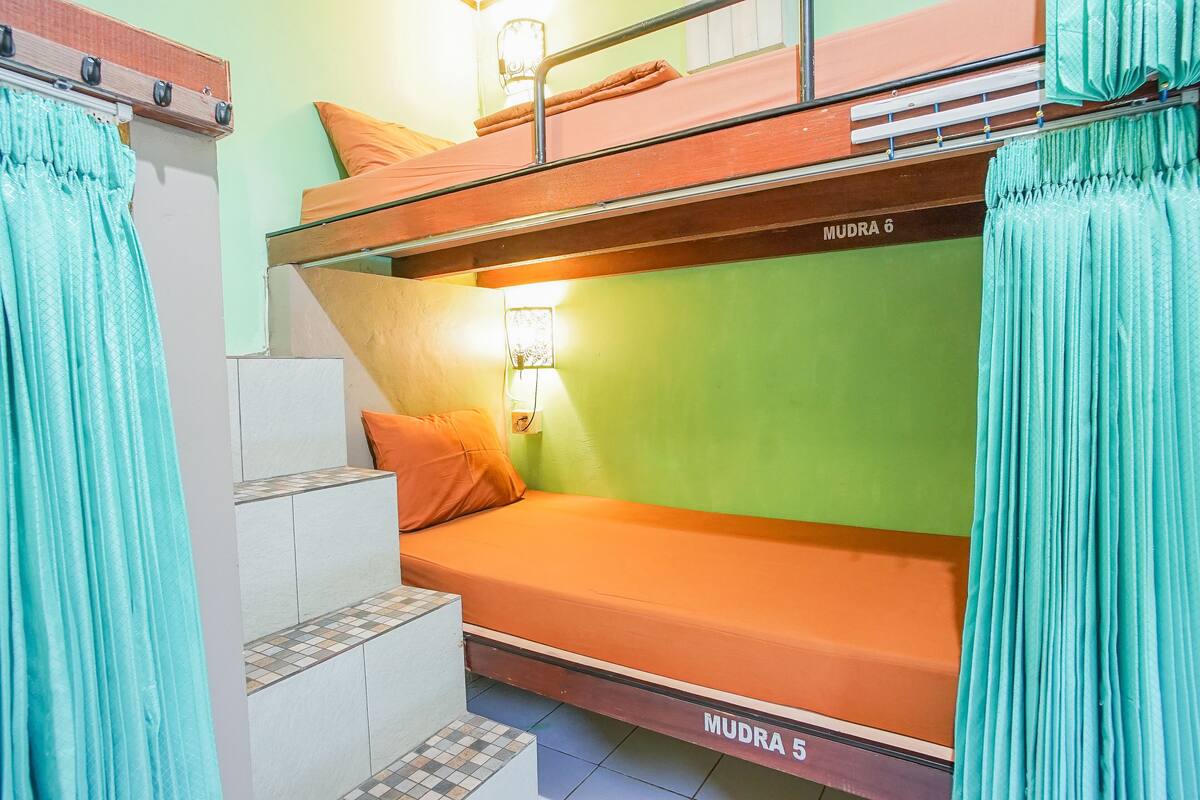 Habitación con literas y una escalera que conduce a una litera inferior con la etiqueta 'MUDRA 5'.