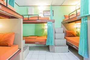 Cozy dormitory-style room with bunk beds and a staircase, featuring a window and a shelf.