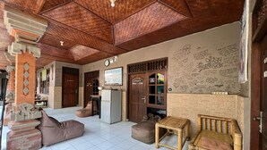 A spacious living area with a tiled floor, a wooden ceiling, and a wall decorated with handwritten notes. - Padi-Padi Hostel & Bar (Ubud)