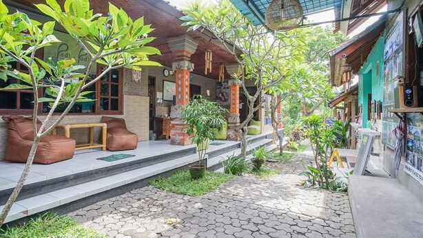 A courtyard with a wooden bench, potted plants, and a tiled walkway. - Padi-Padi Hostel & Bar (Ubud)