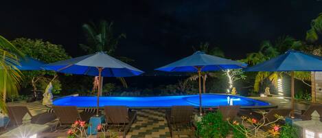 A pool area with lounge chairs and umbrellas, surrounded by greenery and decorative elements.