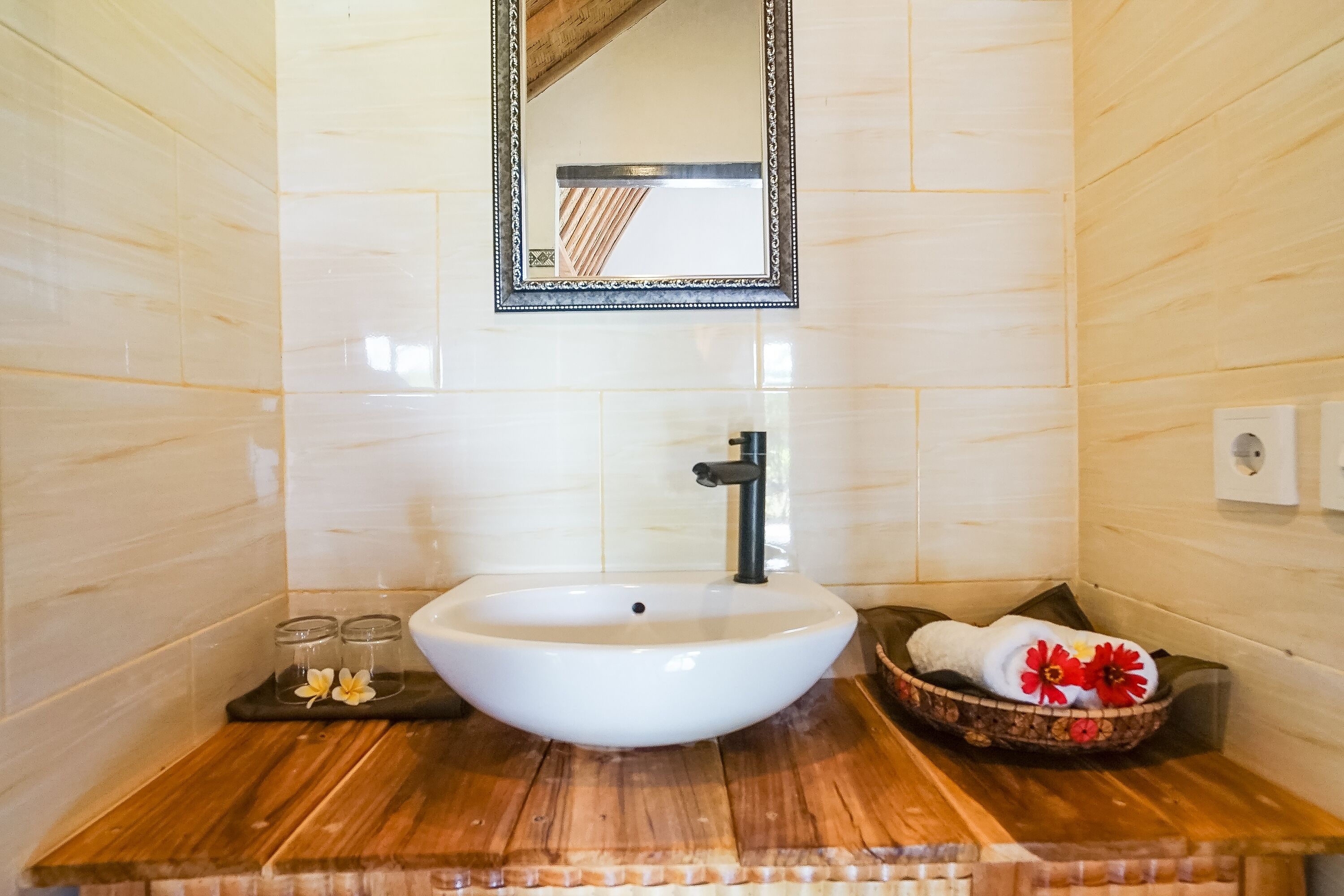 A bathroom with a white sink, wooden countertop, and a mirror above it.