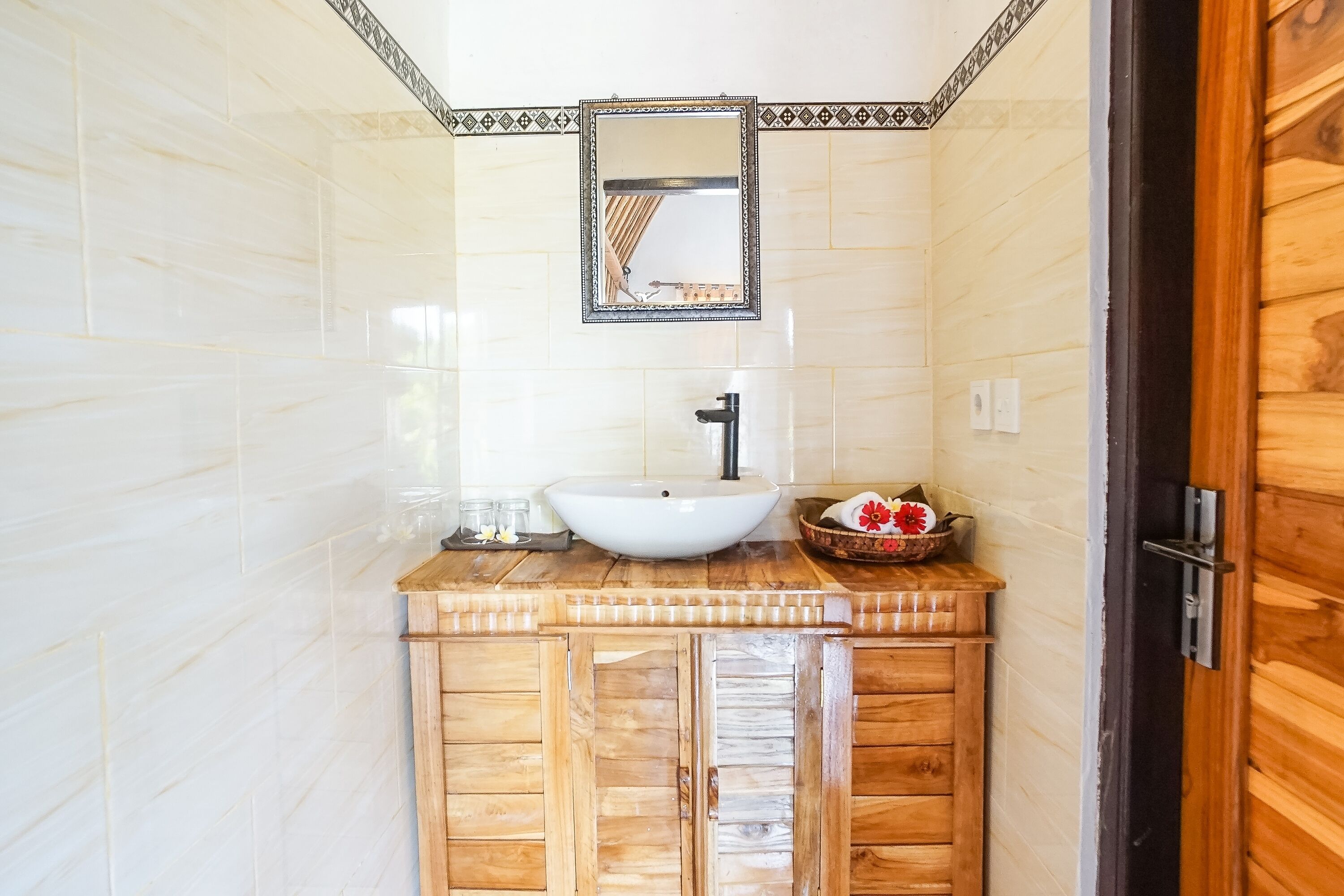 A bathroom with a white sink, wooden cabinets, and a mirror with a decorative frame.