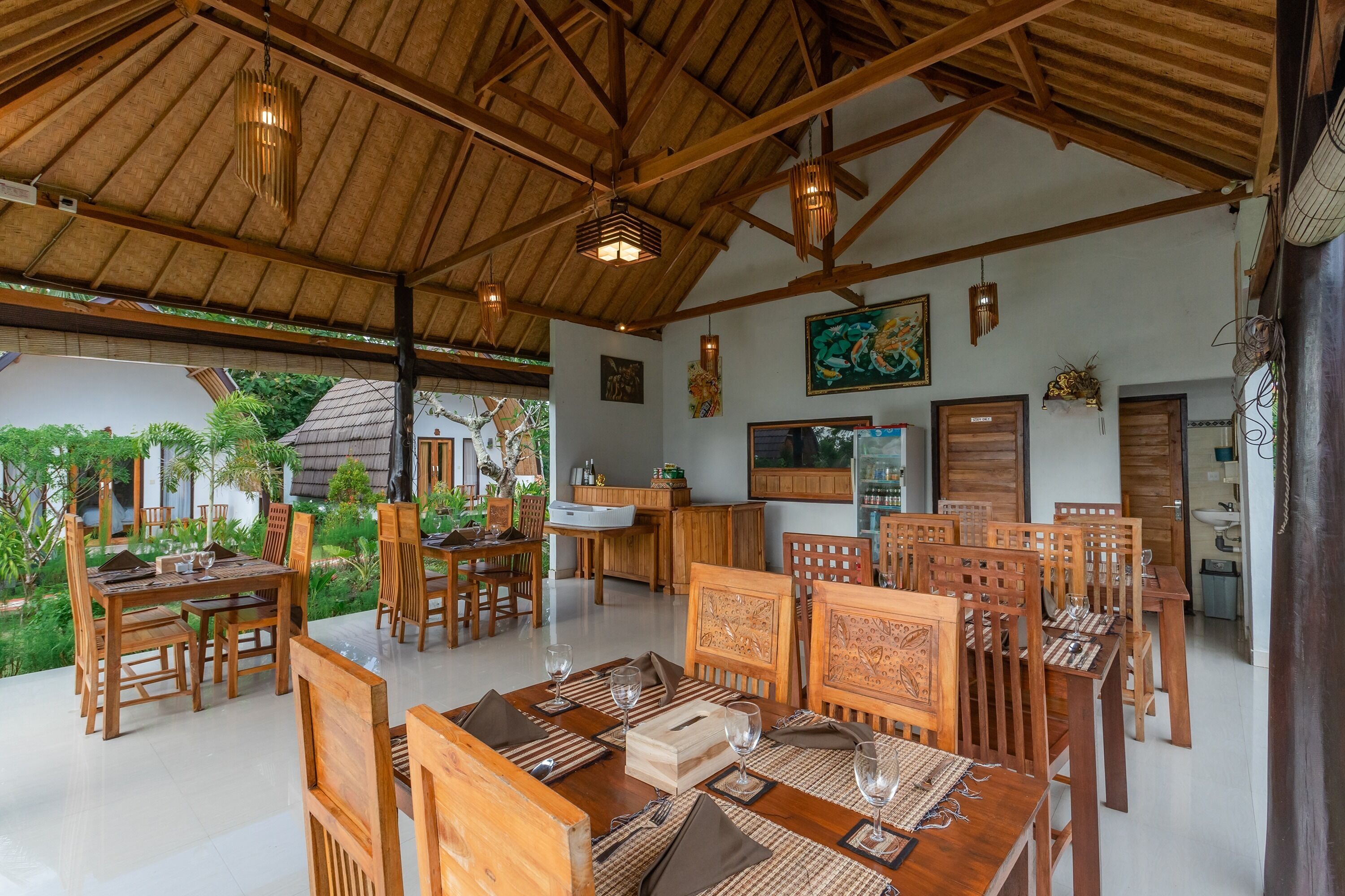 A spacious dining area with wooden furniture and a thatched roof ceiling.
