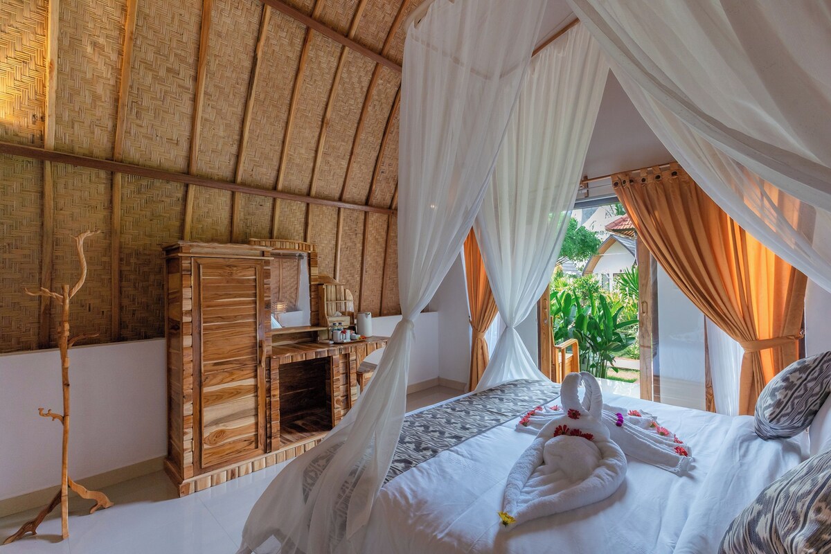 Una habitación con cama, muebles de madera y vista al verde exterior.