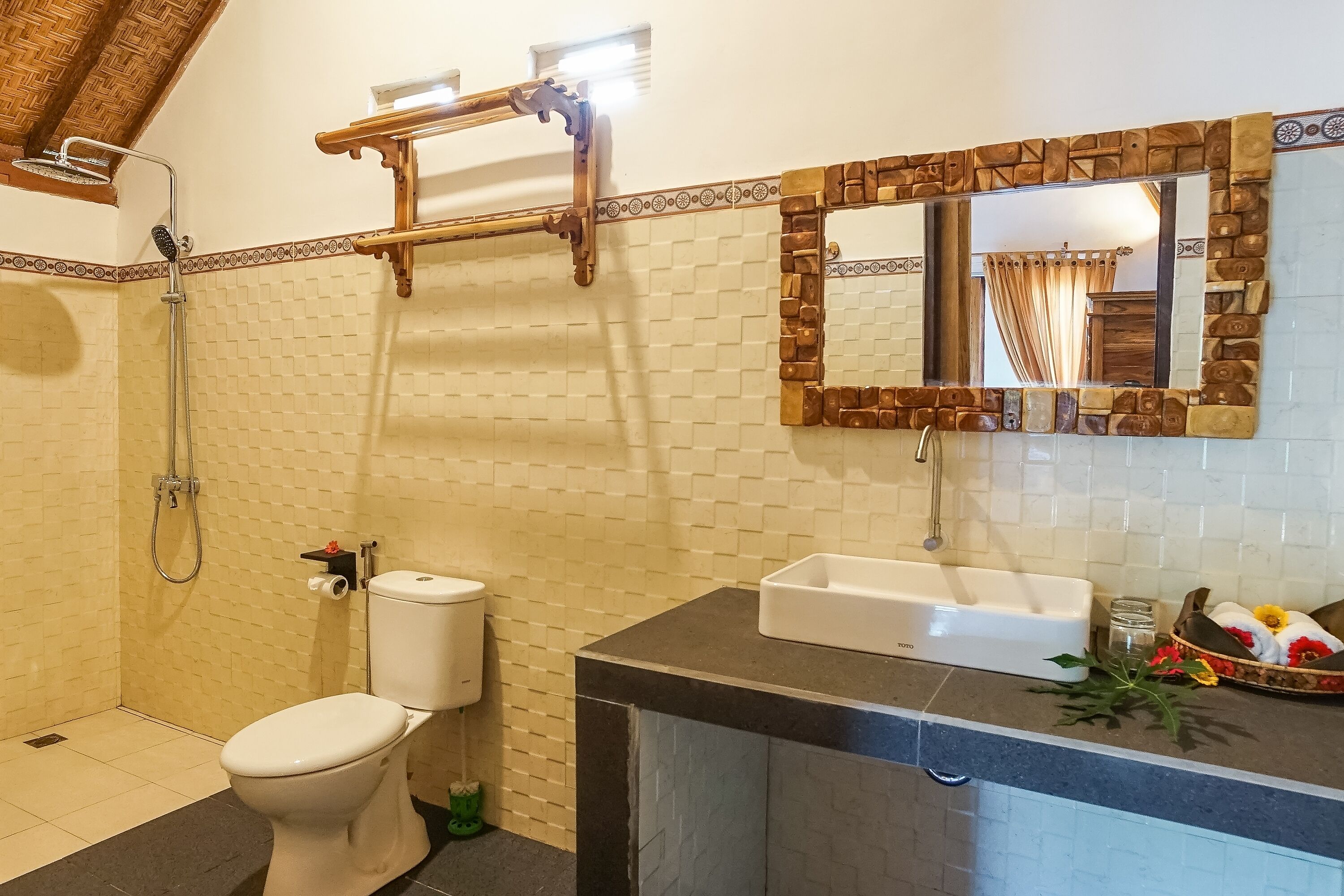 A bathroom with a shower, toilet, sink, and a mirror with a decorative frame.