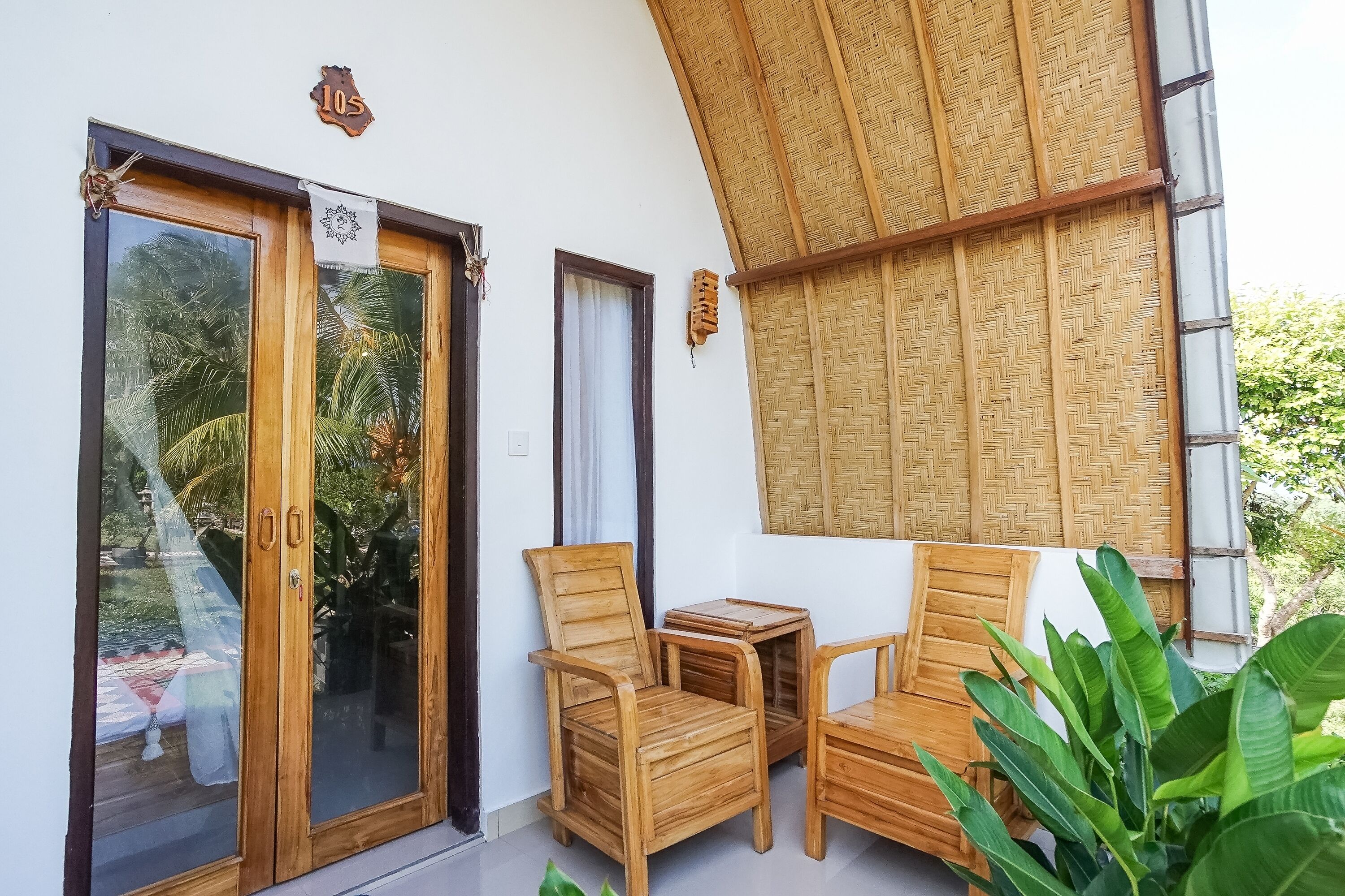 Une pièce aux murs en bois, dotée d’une porte en verre, d’un plafond en osier et d’une petite table en bois, accompagnée de chaises.