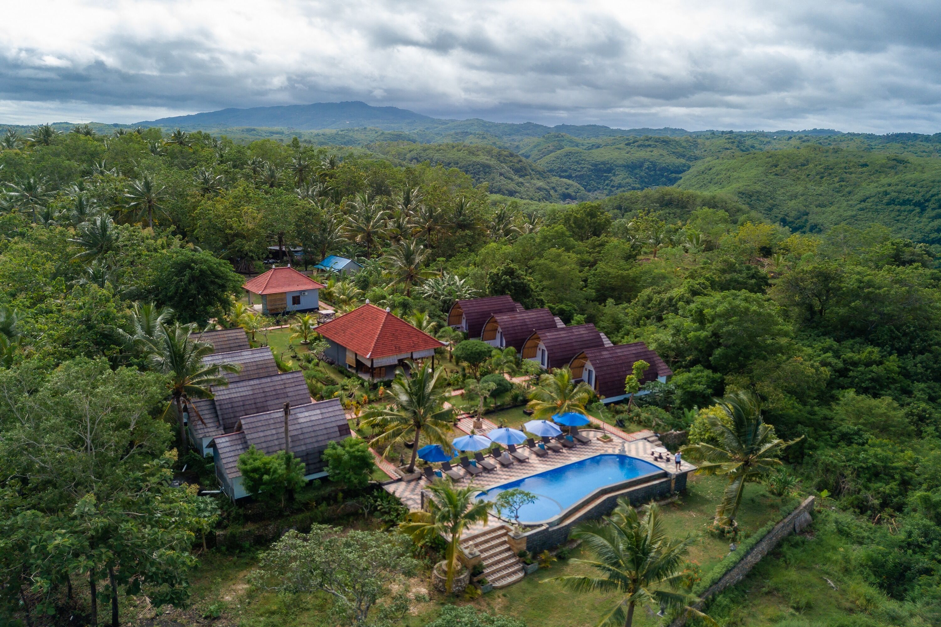 A resort with multiple villas, a swimming pool, and lush greenery.
