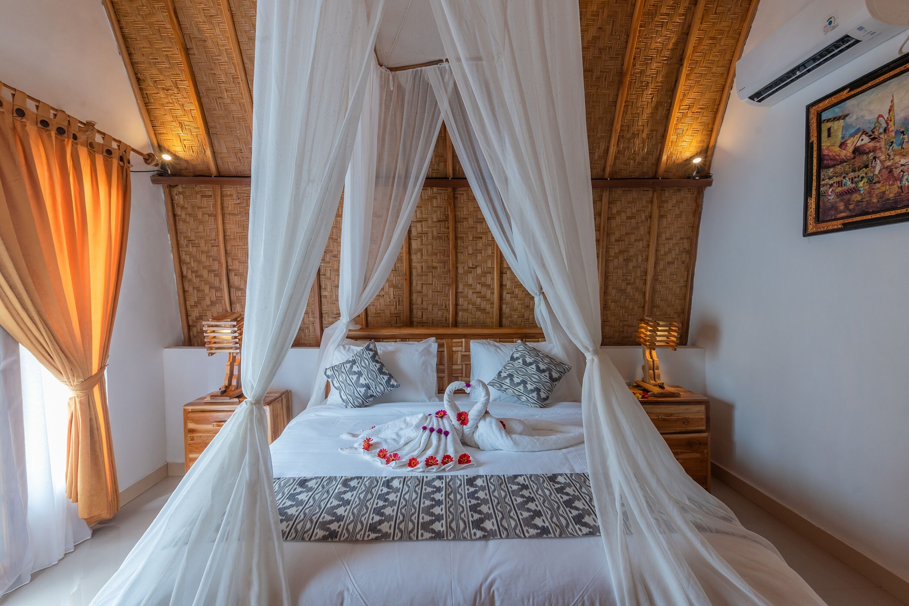 Un dormitorio con cama a dosel, cabecera de madera, dos mesitas de noche con lámparas y aire acondicionado de pared.