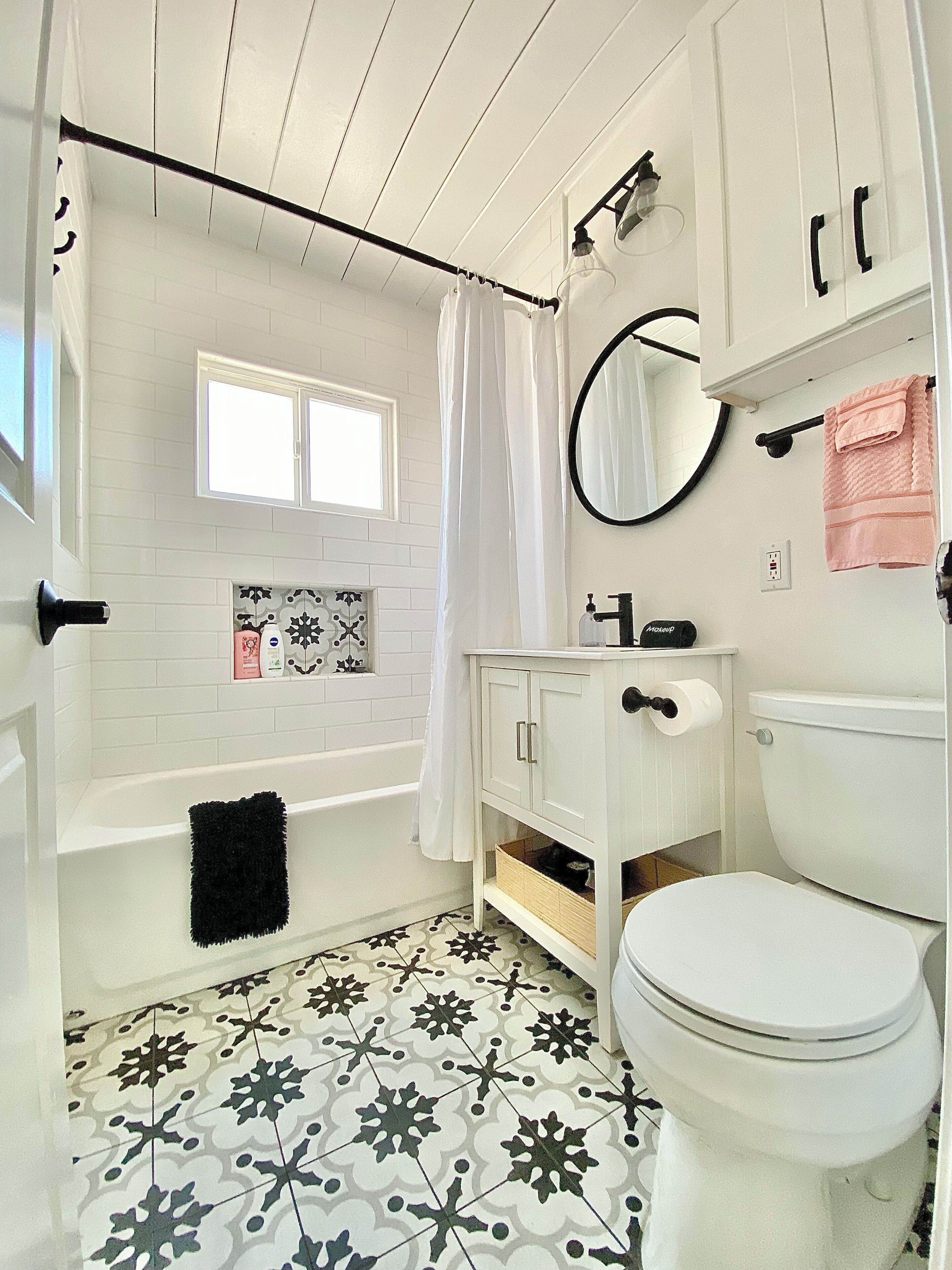 A bathroom with a white bathtub, a toilet, a sink with a mirror, and a shower curtain.