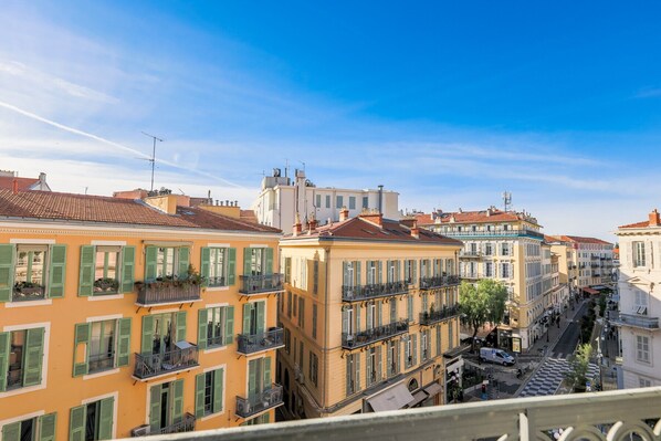 A row of colorful buildings with balconies, a clear sky, and a street below.