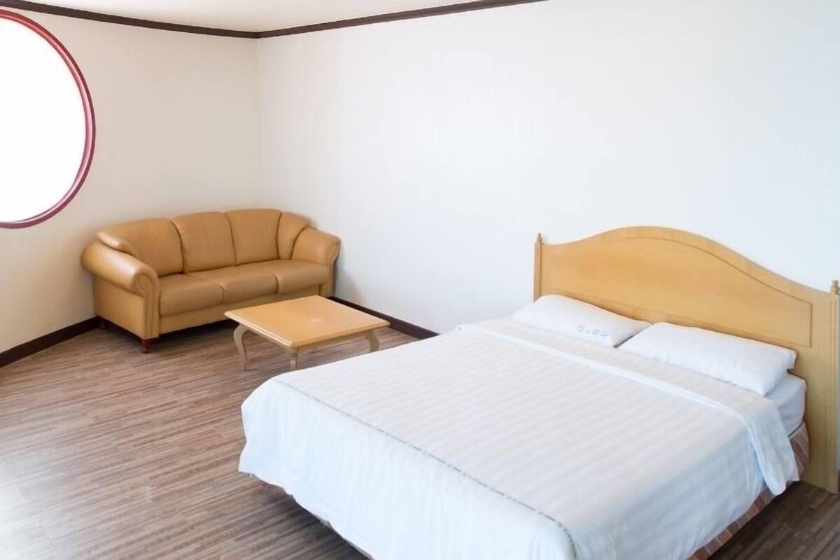 A bedroom with a bed, a sofa, and a small table.