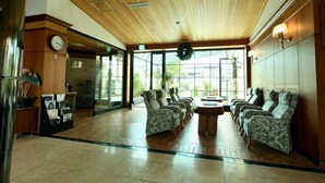 Eine Lobby mit Holzbalkendecke, einer Rezeption, einer Uhr und einer Sitzecke mit gemusterten Stühlen.