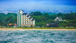 Ein Hotel an der Küste mit mehreren Etagen, einem markanten Turm und Blick auf den Strand.