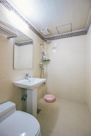 Ein Badezimmer mit Toilette, Waschbecken, Spiegel, Dusche und einem rosa Becken.