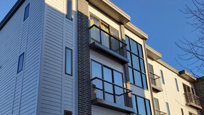 A modern multi-story building with a mix of brick and siding exterior, large windows, and balconies. - Capri 107 Downtown Traverse City  (Traverse City)