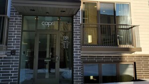 A modern building with a glass entrance labeled "Capri" and multiple balconies. - Capri 107 Downtown Traverse City  (Traverse City)