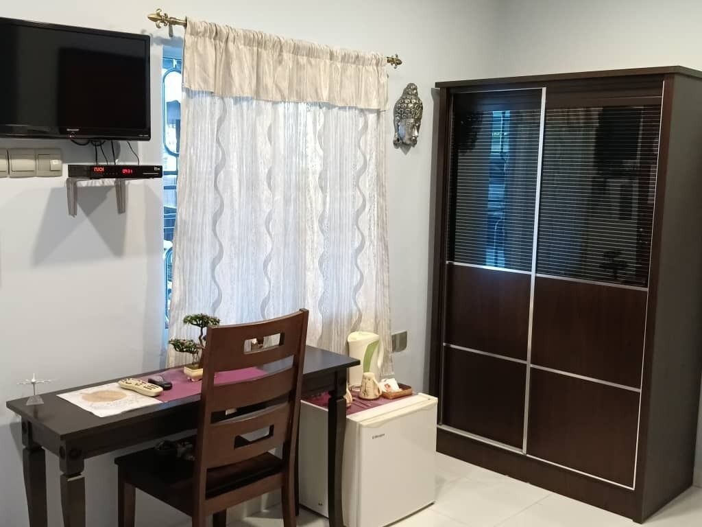 A small room with a desk, chair, television, and a wardrobe with a mirror.