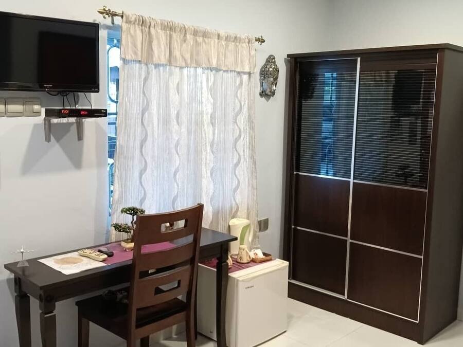 A small room with a desk, chair, television, and a wardrobe with a mirror.