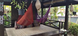 A hammock lounge with a woven seat, a small table with decorative pillows, and hanging planters. - Ocean Lodge (Langkawi)