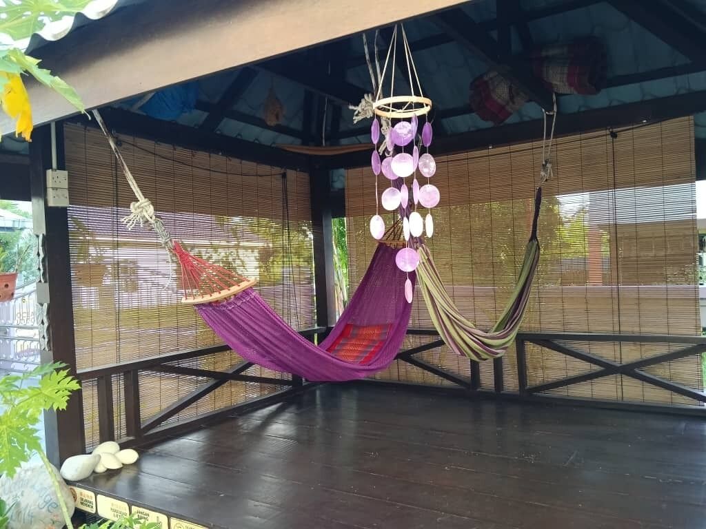Una hamaca colgada del techo, una lámpara colgante y una ventana con marco de bambú.