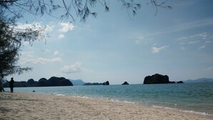 A beach with clear water, sandy shore, and distant rocky islands. - Ocean Lodge (Langkawi)