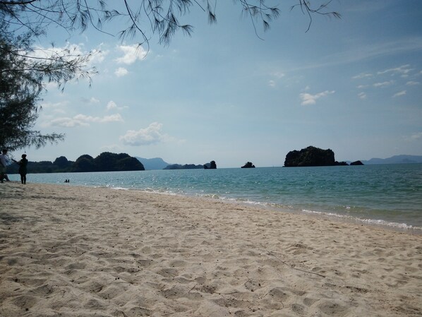 A beach with clear water, sandy shore, and distant rocky islands. - Ocean Lodge (Langkawi)