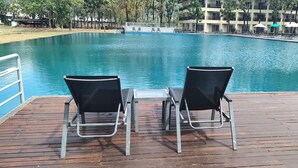 A wooden deck with a pool, two black chairs, and a table. - Ocean Lodge (Langkawi)