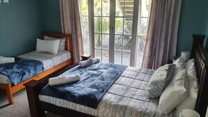 Une chambre d’hôtel avec deux lits simples, un grand lit et une fenêtre avec des rideaux.