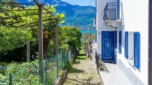 A narrow cobblestone street with a white building featuring blue shutters and a blue door. - Nice apartment for 5 people with WIFI, TV, balcony and pets allowed (Gera Lario)