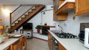 A kitchen with wooden cabinets, a gas stove, a microwave, and a dining area with a table and chairs. - Beautiful apartment for 5 guests with WIFI, TV and pets allowed (Vercana)