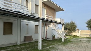 A building with a covered outdoor area, a staircase, and a small garden. - M150 - Marcelli, two-room apartment directly on the beach (Marcelli)