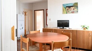 Ein Essbereich mit Holztisch und -stühlen, einem Fernseher auf einer Holzkommode und einem Bild an der Wand.