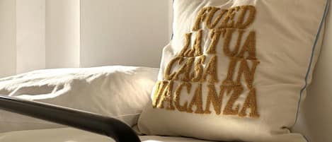 Una cama con un almohadón que lleva bordado un texto.