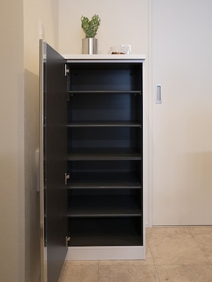 A walk-in closet with multiple shelves and a potted plant on top.