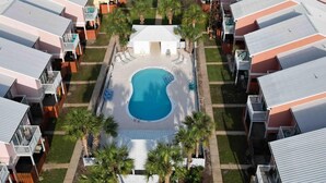 A residential complex with a central swimming pool surrounded by single-story houses with balconies. - 5-Min Walk to Beach | Pool | Loaded Game Room | Near Shops & Outlets ✨ (Miramar Beach)