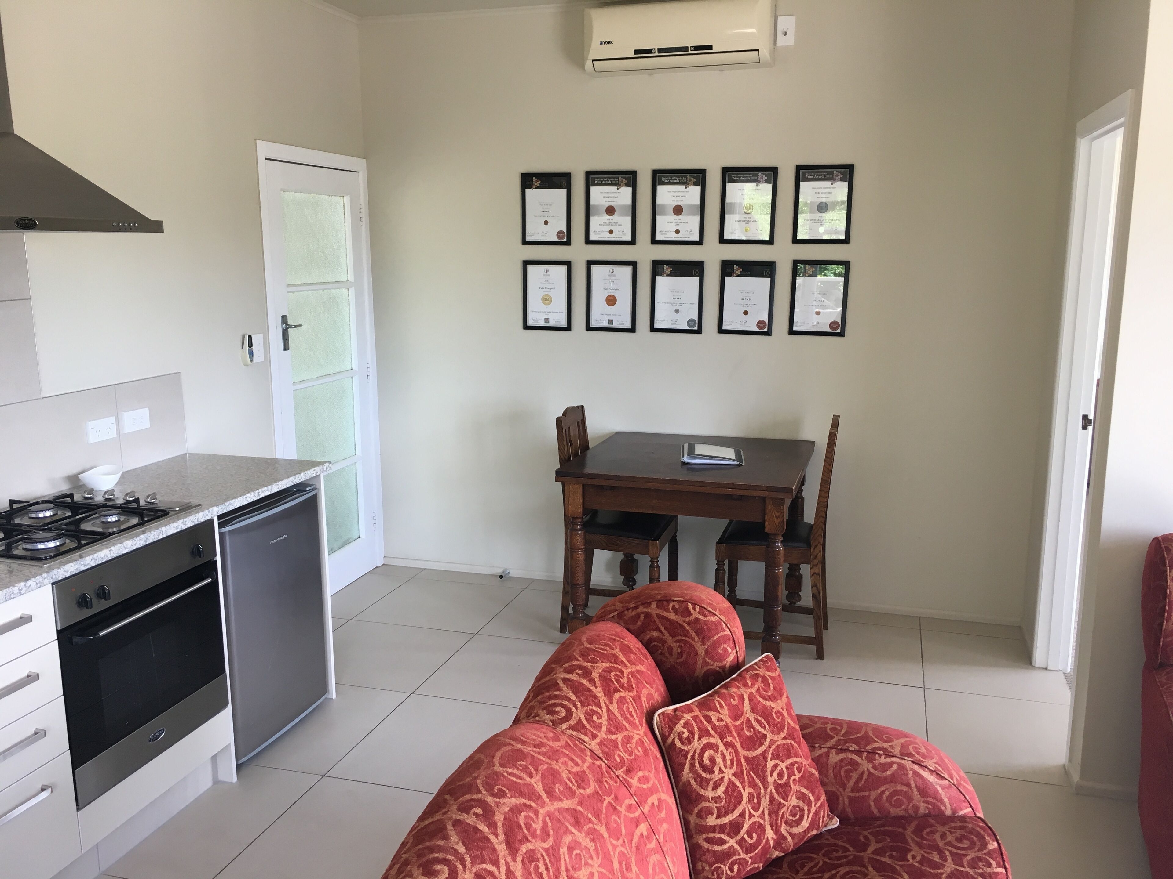 A compact kitchen with a gas stove, oven, and dishwasher, a dining table with chairs, and a sofa in the living area.