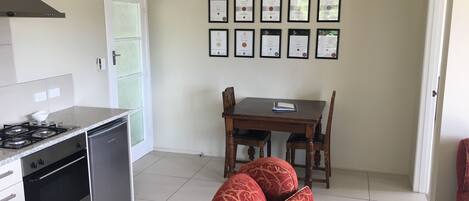 A compact kitchen with a gas stove, oven, and dishwasher, a dining table with chairs, and a sofa in the living area.