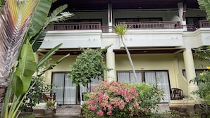 A two-story building with a balcony, surrounded by tropical plants and a small garden. - Sea Breeze Bungalow (Koh Samui)