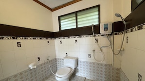 A bathroom with a toilet, shower, and a window with blinds. - Sea Breeze Bungalow (Koh Samui)